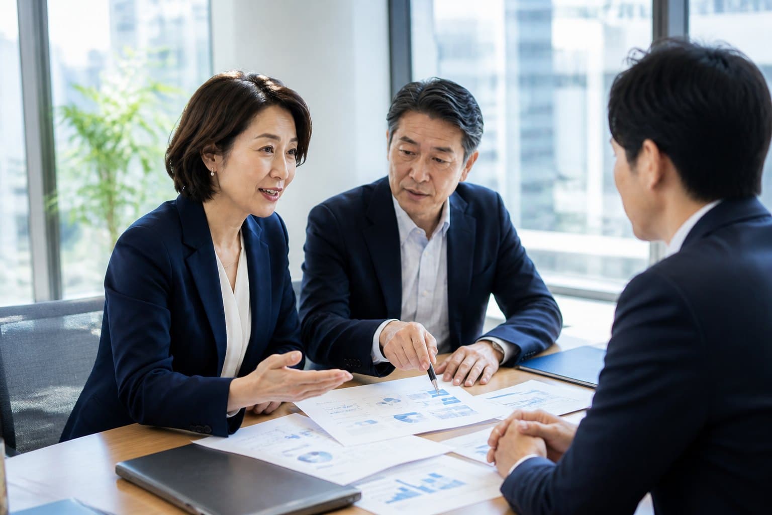 会議室で資料を広げ、狙う相手について話す企業の担当者と顧問